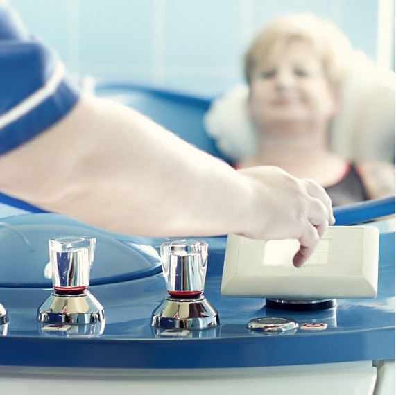 Hydroterapia - kąpiel perełkowa. Fizjoterapeutka włącza zabieg pacjentce leżącej w wannie