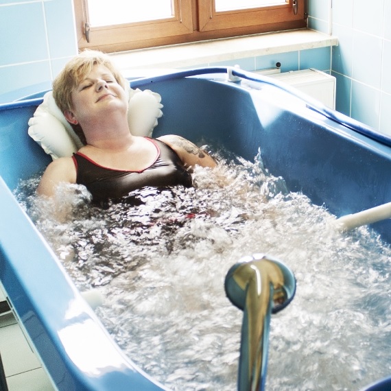 Hydroterapia - hydromasaż. Pacjentka leży w wannie z hydromasażem.
